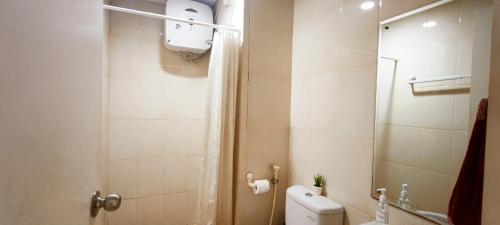 a small bathroom with a toilet and a shower at Vast! Metro Park Manhattan 2BR in Jakarta