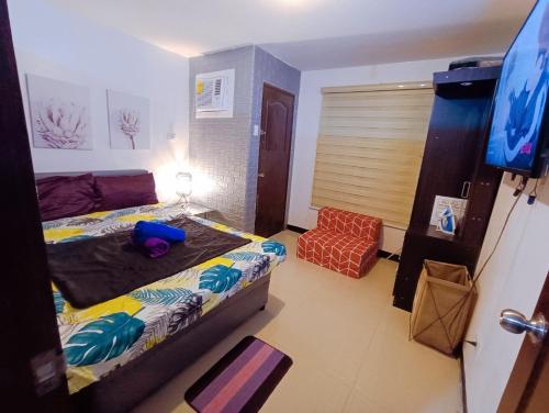 ein Schlafzimmer mit einem Bett, einem Stuhl und einem TV in der Unterkunft UNO'S Place with Karaoke,Wifi,Netflix and Balcony in Anabu Primero