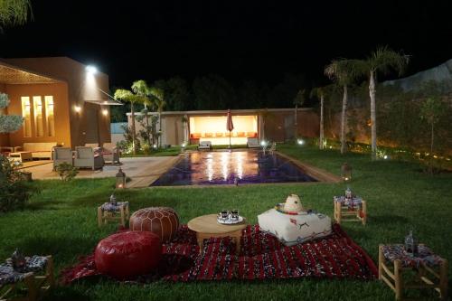 un patio trasero por la noche con una mesa y una piscina en Villa Treasure of Marrakech, en Marrakech