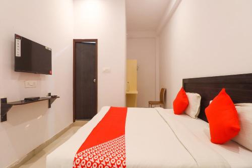 a bedroom with a bed with red pillows and a tv at OYO Flagship Metro Inn in Chinhat