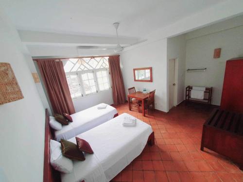 a hotel room with two beds and a table at Mount Bay Guest House in Mount Lavinia
