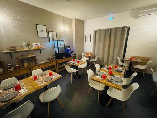a dining room with tables and white chairs at Hôtel De La Loge in Perpignan