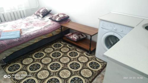 ein kleines Zimmer mit einem Bett und einer Waschmaschine in der Unterkunft 1 комнатные апартаменты возле ст. метро Москва in Almaty