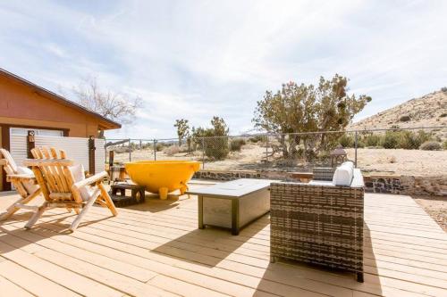 a wooden deck with chairs and a yellow bowl on it at JT's Star Catcher Cabin - HOT TUB in Yucca Valley