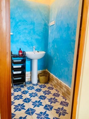 a bathroom with a sink and a blue wall at Nakupenda House in Jambiani