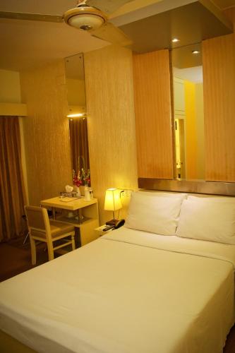 a bedroom with a bed and a desk and a table at Hotel Ornate in Dhaka