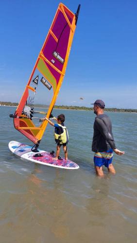 a man and a child with a sail on a surfboard at De Silva Palm Resort in Kalpitiya
