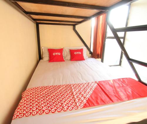 a bed in a room with two red pillows at OYO 93121 Abi Bungalow & Hostel in Pawenang