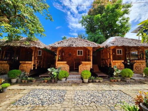 a house with thatched roofs and potted plants at Uno Dus Tourist Inn in Itaytay