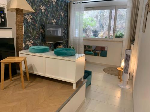 d'un salon avec une commode dotée d'oreillers bleus et d'une télévision. dans l'établissement L'îlot Bornala, à Nice