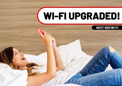 a woman laying on a bed with her phone at Red Planet Ortigas in Manila