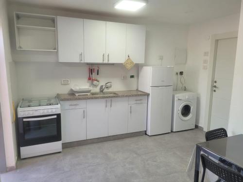 a kitchen with white cabinets and a washer and dryer at Newly Renovated Home in Bet Shemesh Vatika in Beit Shemesh