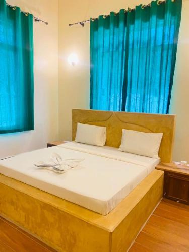 1 dormitorio con 1 cama grande y cortinas azules en Nakupenda House en Jambiani