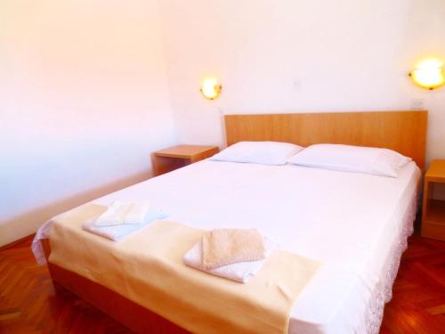 een slaapkamer met een wit bed met handdoeken erop bij Apartments Toncic in Lumbarda