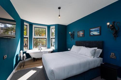 a blue bedroom with a bed and a tub and a sink at 23 Trafalgar Square with hot tub and cinema in Scarborough