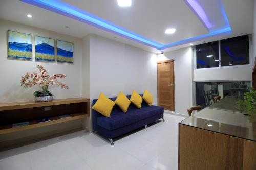 - un salon avec un canapé bleu et des oreillers jaunes dans l'établissement Hostal Plaza by Elvita, à Baños