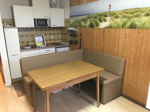 a small kitchen with a wooden table and a bench at Ferienanlage Achtern Diek in Thalingburen