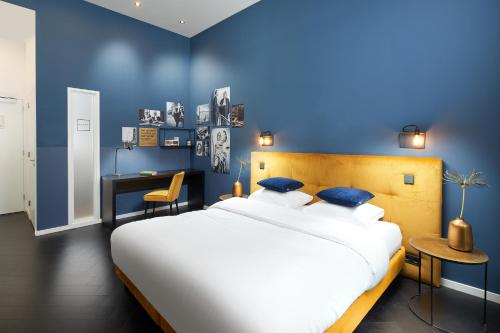 a blue bedroom with a large bed and a desk at Court Hotel Utrecht City Centre in Utrecht
