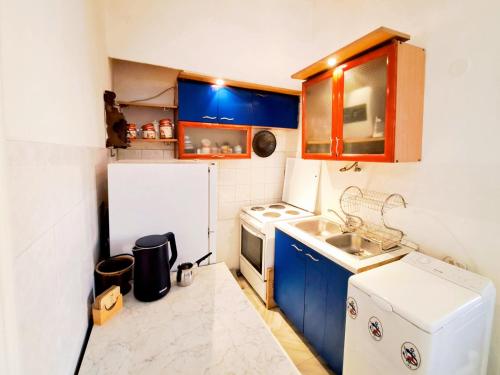 a small kitchen with blue cabinets and a white refrigerator at River Side Belgrade in Sajmište