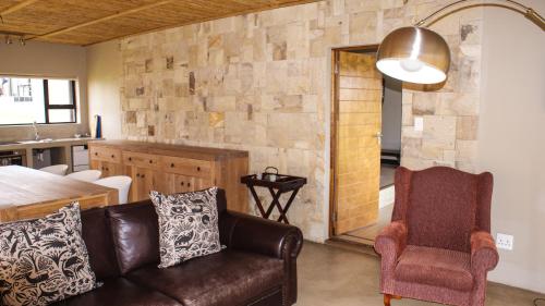 a living room with a leather couch and a kitchen at Umbono Private Game Lodge in Alexandria