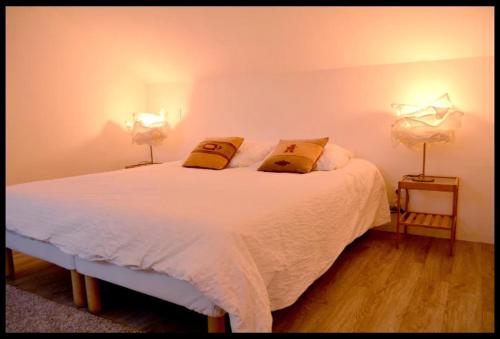 1 dormitorio con 1 cama blanca y 2 lámparas en L'Atelier de la Blanchardière 49520, en Le Tremblay