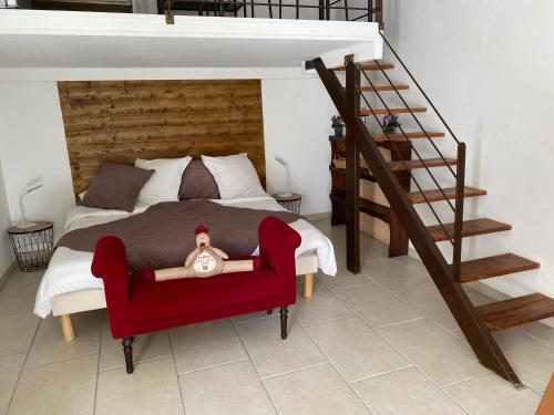 um quarto com uma cama com uma cadeira vermelha e uma escada em Mas des Bômes **** em Mérindol