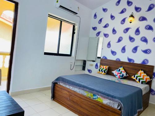 a bedroom with a bed and a blue and white wall at Highland Beach Apartments Goa in Baga