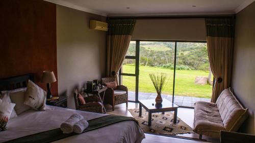 a bedroom with a bed and a couch and a large window at Umbono Private Game Lodge in Alexandria