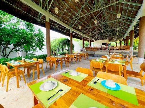 a restaurant with wooden tables and chairs and a tables and chairs at Me Bungalow Beach Resort in Phan Thiet