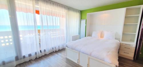 une chambre avec un lit blanc et une grande fenêtre dans l'établissement Beautiful Vacation Rental in Le Barcars, France, au Barcarès