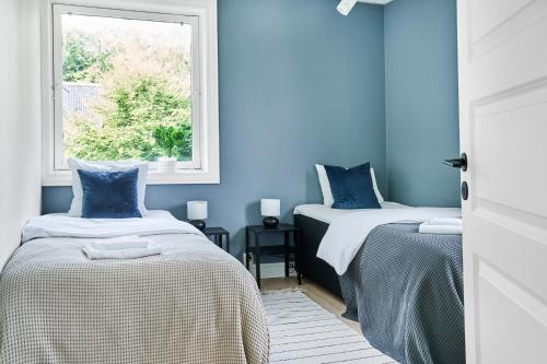 a blue room with two beds and a window at Queen's Cave By Staysville in Stavanger