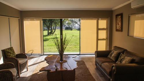 a living room with a couch and a large window at Umbono Private Game Lodge in Alexandria