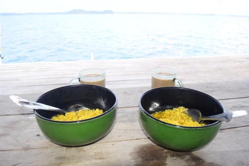 zwei Schüsseln Essen auf einem Tisch mit Getränken in der Unterkunft Kelong Bintan in Teluk Bakau