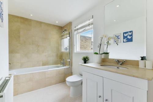 a bathroom with a toilet and a sink and a tub at Knightsbridge Stylish Two Bedroom Apartment in London