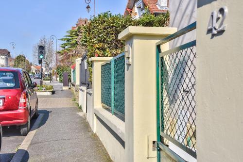 a red car parked on a street next to a fence at Promotion du Jour - Studio Le Palmier in Deuil-la-Barre