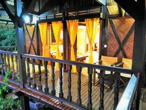 a porch of a wooden house with orange curtains at Fleurdesiles in Nosy Be