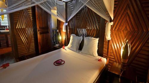 a bedroom with a bed with white sheets and pillows at Fleurdesiles in Nosy Be
