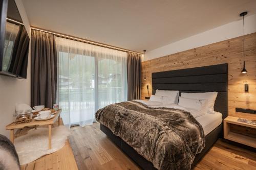 een slaapkamer met een groot bed en een groot raam bij Vista Chalets Sexten in Sesto