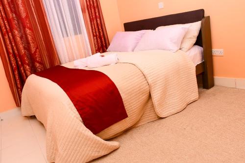 a bed with a red and white blanket on it at The Lotus Stay-in at Paradise Apartments, Embu in Embu