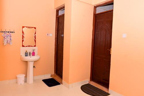 a bathroom with a toilet and a sink and a door at The Lotus Stay-in at Paradise Apartments, Embu in Embu