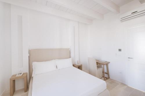 a white bedroom with a white bed and a window at Tra Cielo e Mare in Vieste