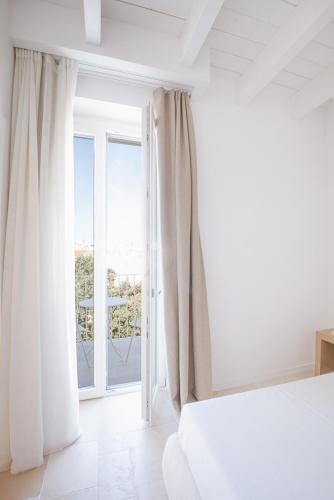 a white bedroom with a bed and a large window at Tra Cielo e Mare in Vieste