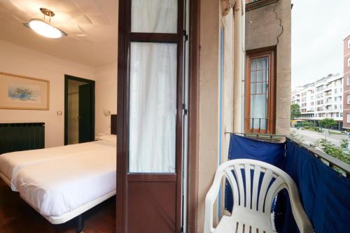 a bedroom with a bed and a chair on a balcony at Pension Areeta in Getxo