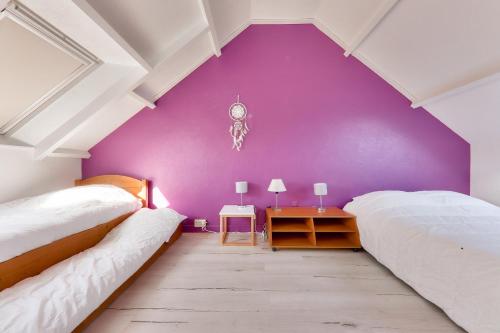 - 2 lits dans une chambre dotée d'un mur violet dans l'établissement Appartement pour 6 - 400 plage du Fogeo, à Arzon