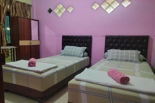 two beds in a room with pink walls at OYO 93071 Home Stay Kembar Syariah in Binjai