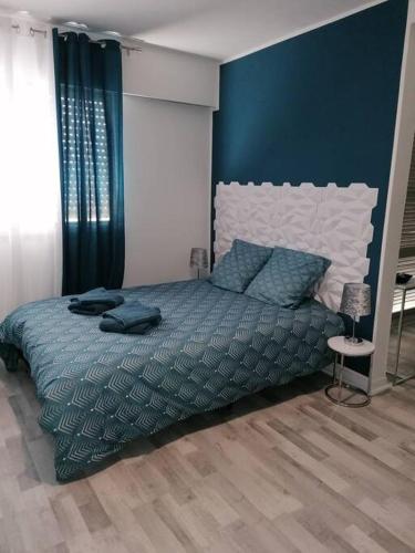 een slaapkamer met een bed met een blauwe muur bij Le belvédère-centre ville in Belfort