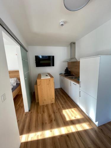 a kitchen with white cabinets and a flat screen tv at Hotel Lercher in Sankt Veit im Pongau