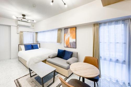 a bedroom with a bed and a couch and a table at Trioni EBISU in Osaka