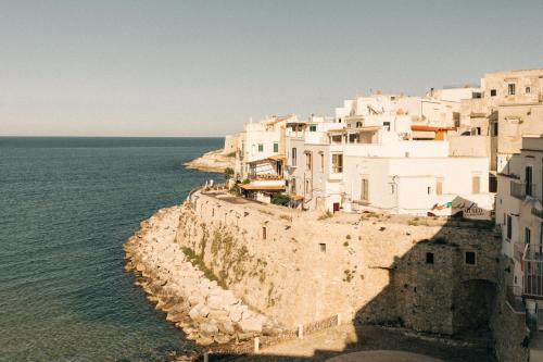 a group of white buildings on a cliff next to the ocean at Tra Cielo e Mare in Vieste