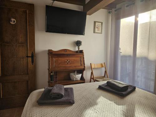 um quarto com uma cama e uma televisão na parede em El Nido, Casa Rural em Casas del Castañar